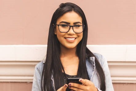 Portrait of a brazilian girl using smartphone looking at you